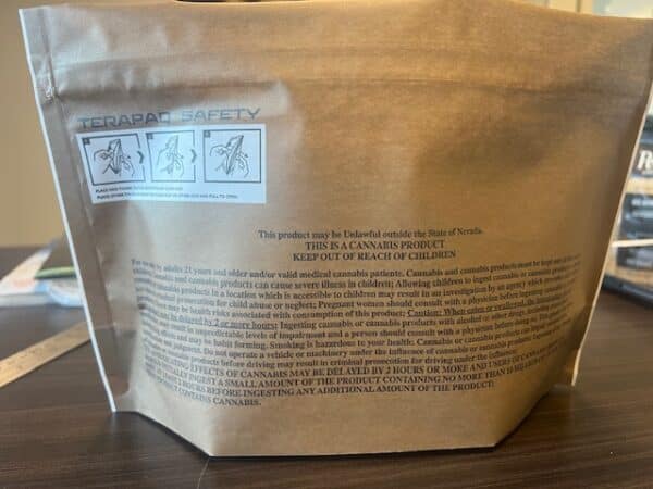 A brown paper bag labeled "TERAPAL SAFETY" with illustrations and safety warnings. Text includes product information, age restrictions, and a "KEEP OUT OF REACH OF CHILDREN" notice. The bag is on a wood surface in an indoor setting.