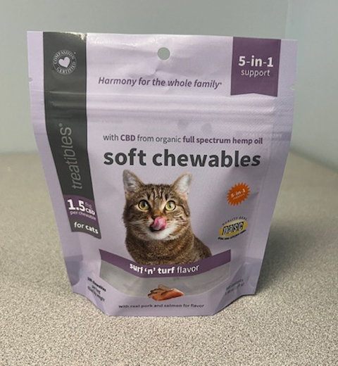 A packet of "soft chewables" for cats is displayed. The packaging is purple with a photo of a cat. It is labeled "surf 'n' turf flavor," containing CBD from organic hemp oil and claiming "5-in-1 support.