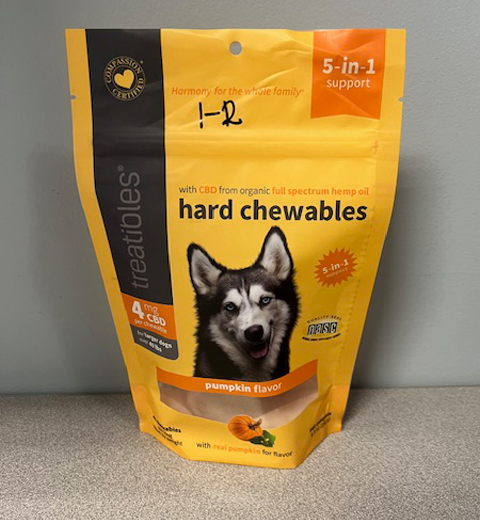 A package of Treatibles Hard Chewables for dogs in pumpkin flavor is displayed. The packaging shows a dog illustration and mentions it contains 4 mg of CBD per chew, promoting 5-in-1 support with ingredients like full-spectrum hemp oil.